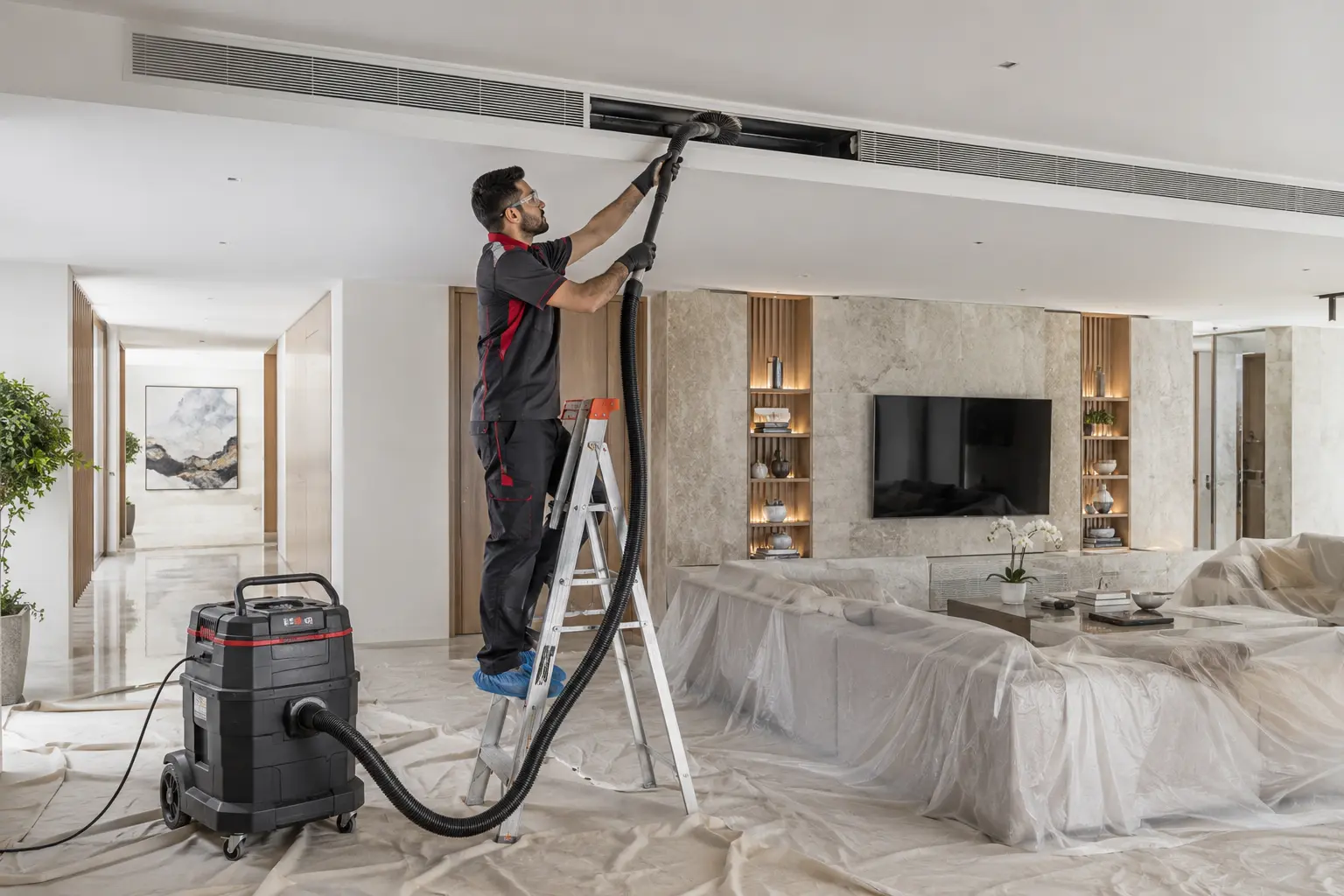 Technician cleaning an accessible ceiling AC duct with connected professional equipment