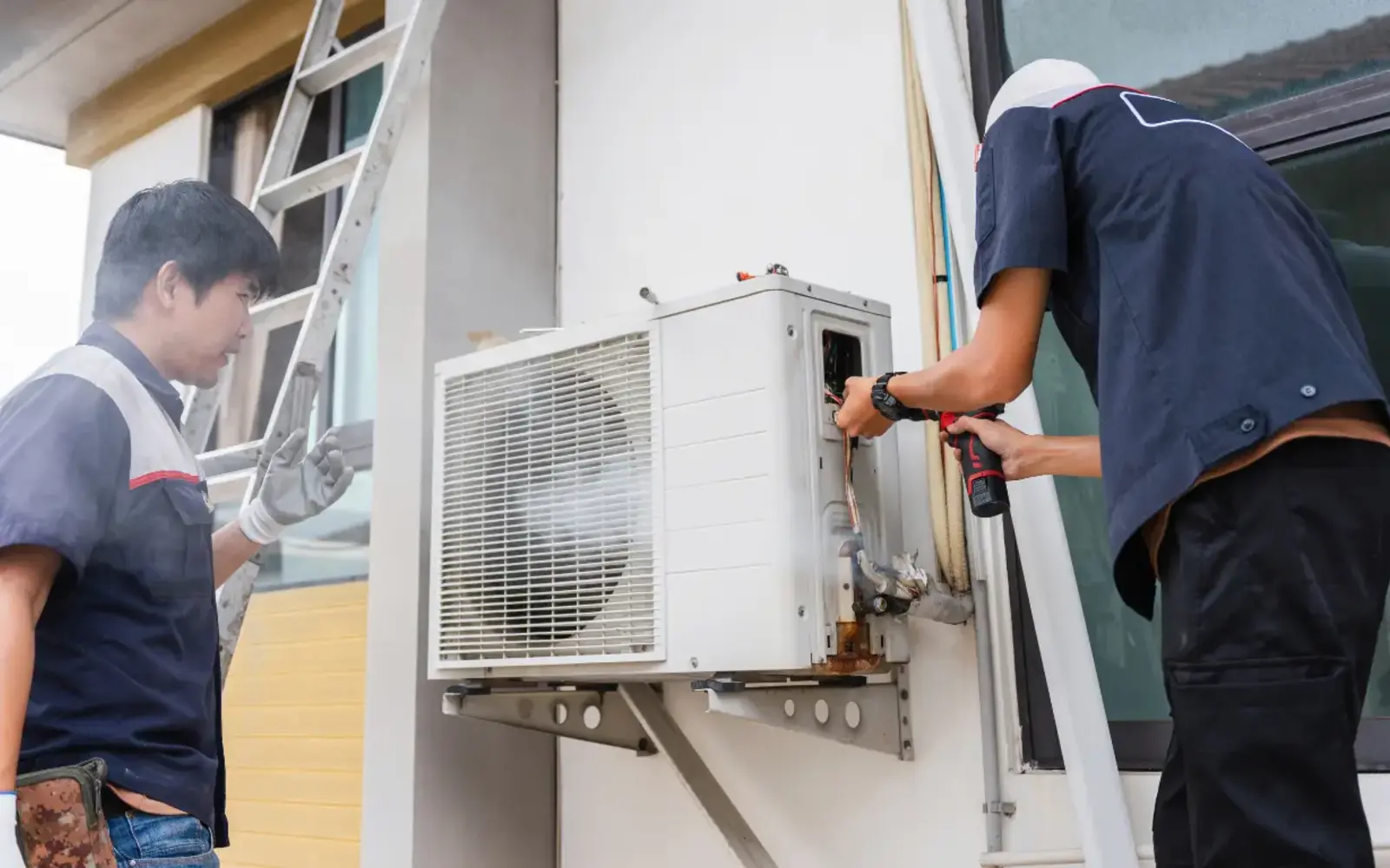 Technicians inspecting an outdoor air-conditioning unit