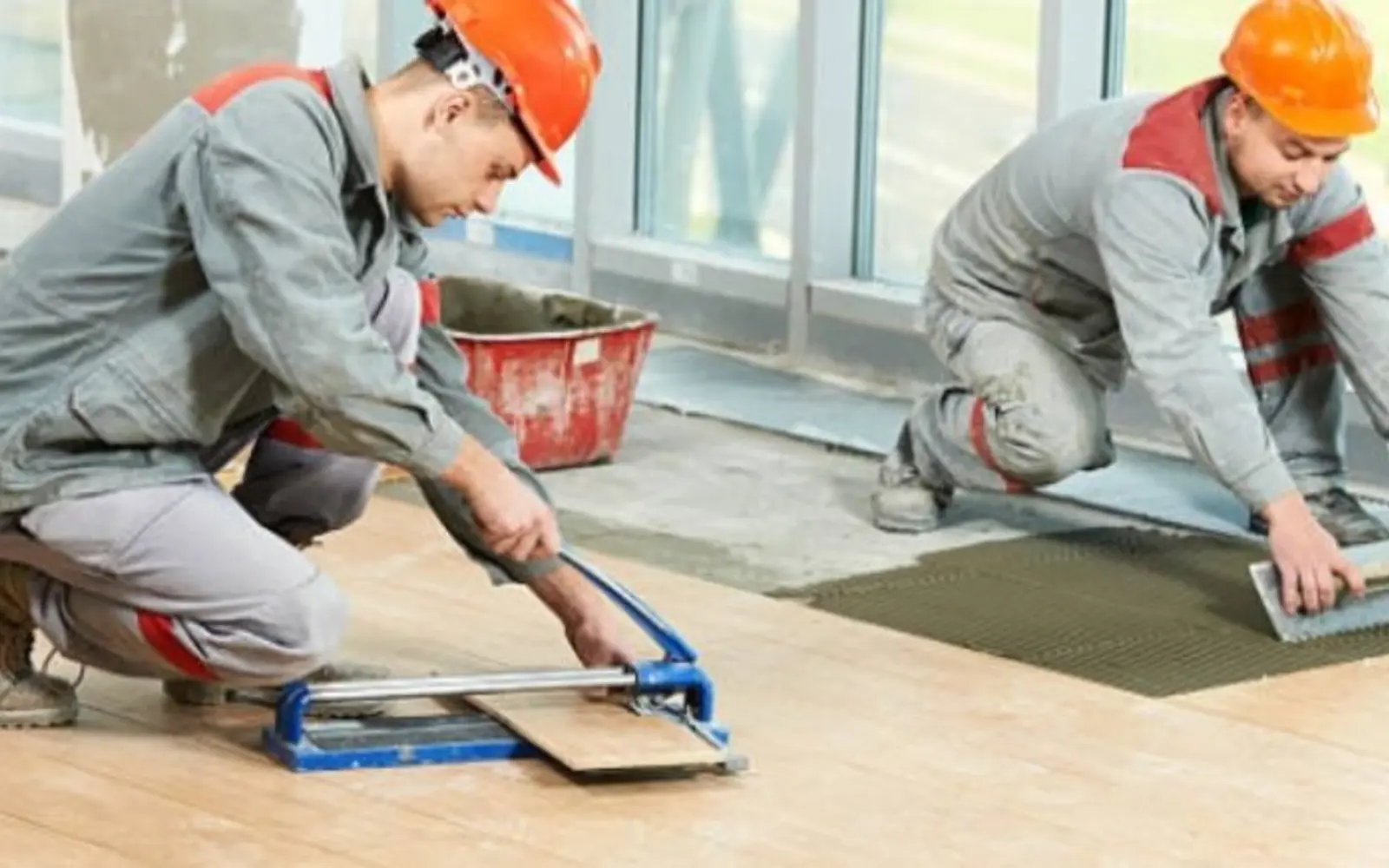 Tile installers aligning large floor tiles during renovation